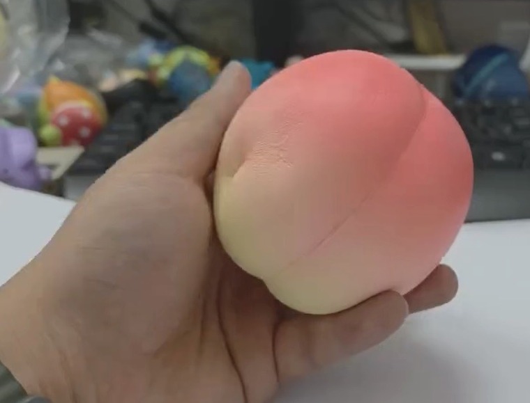 手のひらに桃スクイーズをのせた様子